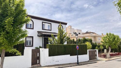 une maison blanche avec un portail et une clôture dans l'établissement Extraordinaria Villa con piscina y chimenea, à Grenade