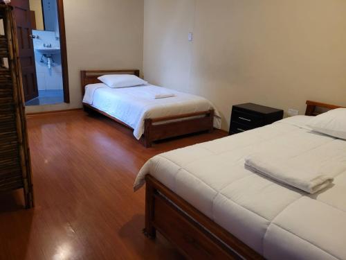 a hotel room with two beds and a mirror at Casa Colon Quito Bed & Breakfast Hostel in Quito