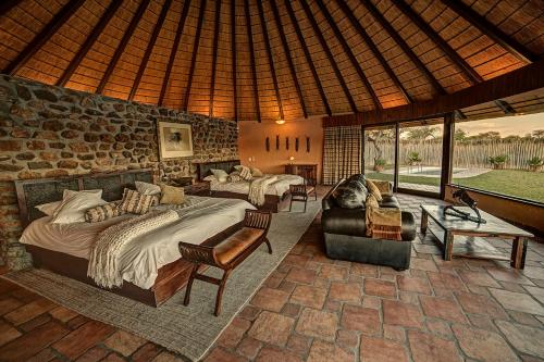 a bedroom with two beds and a stone wall at Mount Etjo Safari Lodge in Kalkfeld