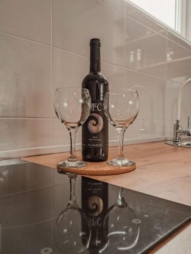 a bottle of wine and two wine glasses on a counter at Apartman Hači in Kolašin