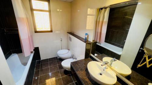 Un baño con dos lavabos y un inodoro. en Khaliq Basera, en Dubái