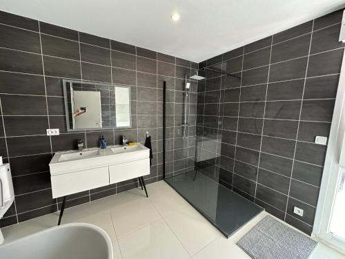 a bathroom with black tiled walls and a sink at Maison individuelle à 8 minutes d'Ouistreham, quartier calme, transports en commun Tram & Bus, commerces de proximités in Hérouville-Saint-Clair