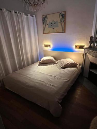 - une chambre avec un lit blanc et une lumière bleue dans l'établissement Grande chambre privée sur jardin arboré, à Paris
