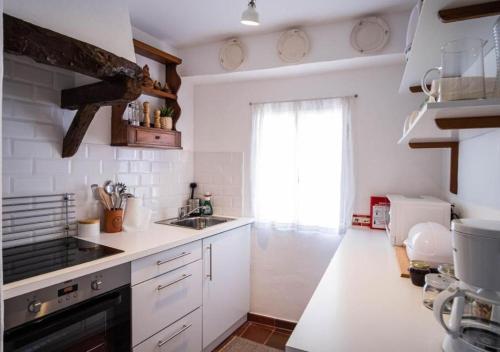 a white kitchen with a sink and a window at Casa do Largo in Torres Vedras