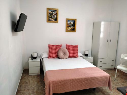 a small bedroom with a bed with red pillows at El Rinconcito de Ensueño in Gran Tarajal