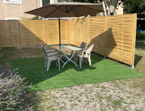 a table with chairs and an umbrella on a patch of grass at Maison indépendante dans Mas Provençal in Avignon