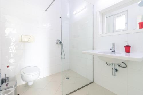 a white bathroom with a toilet and a sink at Apartments FourRoses in Ulcinj