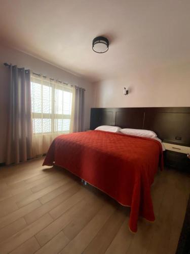 a bedroom with a red bed and a window at Apartamento #12 Portal de Occidente in Quetzaltenango