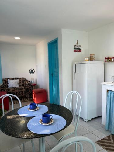 a kitchen with a table and chairs and a refrigerator at Casa da Bru pertinho da praia e da lagoa in Rio das Ostras