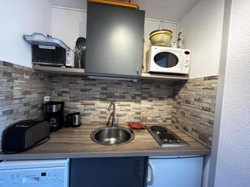une cuisine avec un évier et un micro-ondes dans l'établissement Résidence Chaviere - Au coeur des Menuires appartement 2 pers MAE-4294, aux Menuires