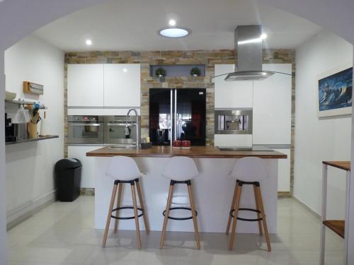 une cuisine avec des armoires blanches et des tabourets de bar dans l'établissement Maison L'Ollivia - Terrasse - Parking gratuit, à Carcassonne