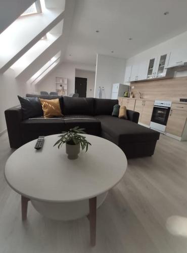 a living room with a black couch and a white table at Krásny nový prízemný apartmán in Nové Zámky