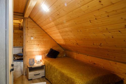 a bed in a room with a wooden wall at Kresy in Wajków