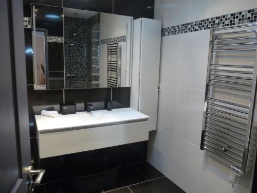 une salle de bain avec un lavabo blanc et un miroir dans l'établissement Maison L'Ollivia - Terrasse - Parking gratuit, à Carcassonne