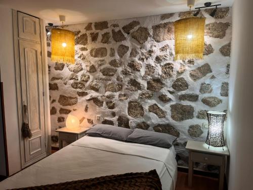 a bedroom with a stone wall with a bed at La cerra -Tiny-house in Mijares