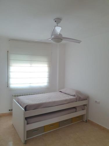 a bed in a white room with a ceiling fan at Lo Piset del Pla in Linyola