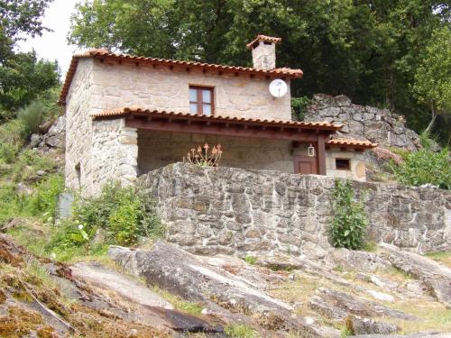 a small stone building with a clock on top of a stone wall at Casa da iapa in Soajo