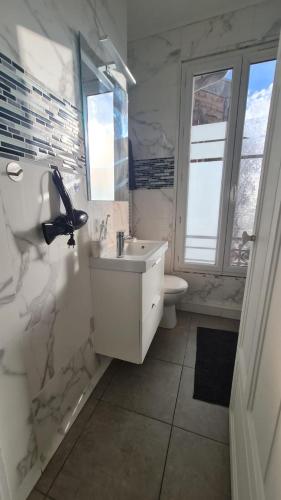 une salle de bain blanche avec un lavabo et des toilettes dans l'établissement Joli Cocon Boulogne Billancourt, à Boulogne-Billancourt