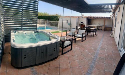 - un bain à remous sur une terrasse avec une table et des chaises dans l'établissement Villa Pura Vida - 6 personnes - piscine, jaccuzi et cuisine d'été, à Velaux