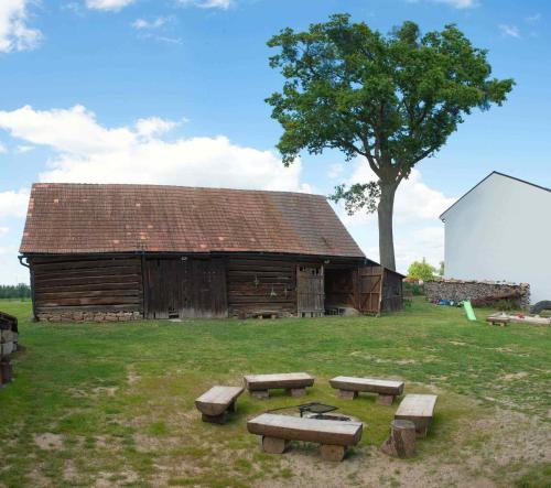 a wooden barn with benches in front of it at Pod Dubem in Veselá