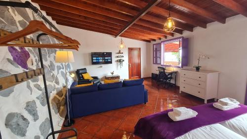 a living room with a blue couch and a bedroom at Los Cerrajones: spectacular views from the cliff in Agulo