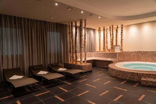 a large bathroom with a jacuzzi tub and chairs at HOTEL POST alpine cityflair in Brunico