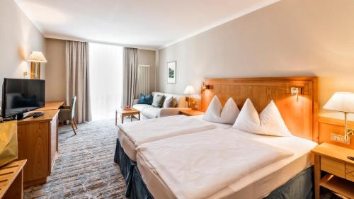 a hotel room with a large bed and a couch at HOTEL POST alpine cityflair in Brunico