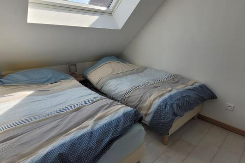 deux lits dans une petite pièce avec une fenêtre dans l'établissement Maison de ville refaite à neuf, à Bourbourg