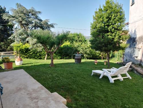 un patio con dos bancos blancos en el césped en Le vigne, en Asti