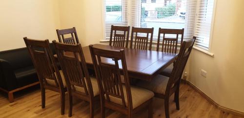 a dining room with a wooden table and chairs at London Luxury 3 bedroom flat, 2 bathrooms, Living Room, free parking, 4 mins to station, garden in Ilford