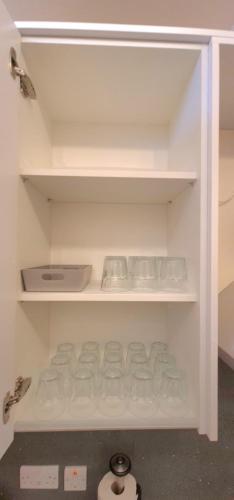 a white shelf with some dishes on it at London Luxury 3 bedroom flat, 2 bathrooms, Living Room, free parking, 4 mins to station, garden in Ilford