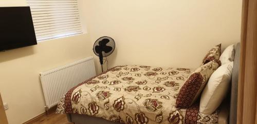 a bedroom with a bed with a comforter and a fan at London Luxury 3 bedroom flat, 2 bathrooms, Living Room, free parking, 4 mins to station, garden in Ilford