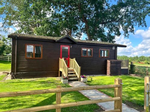 a small cabin with a wooden fence in front of it at Barons Granary, The Chicken Run, Iden near Rye in Iden