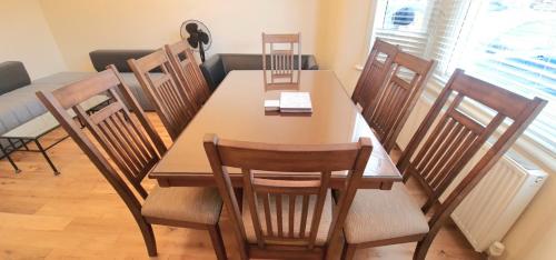 a dining room with a wooden table and chairs at London Luxury 3 bedroom flat, 2 bathrooms, Living Room, free parking, 4 mins to station, garden in Ilford