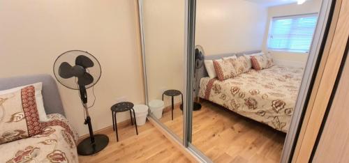 a living room with a couch and a mirror at London Luxury 3 bedroom flat, 2 bathrooms, Living Room, free parking, 4 mins to station, garden in Ilford