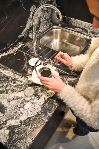 a person is washing a pot in a kitchen sink at La Petite Maison in Tournai
