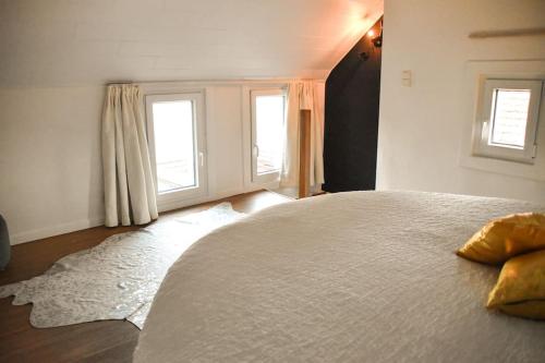 a bedroom with a large bed and two windows at La Petite Maison in Tournai