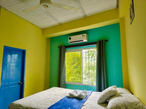 a bedroom with green and yellow walls and a window at El Refugio Minca in Minca