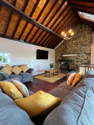 a living room with a couch and a stone wall at Plasbach Cottage in Llandeilo