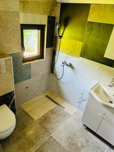 a bathroom with a sink and a toilet and a window at Dolce vita cottage - waterfront in Bihać