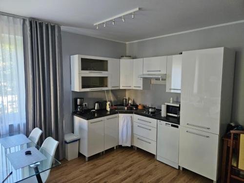 a white kitchen with white cabinets and a table and a table sidx sidx at Apartament Olymp 113 z dwoma sypialniami i basenem in Kołobrzeg