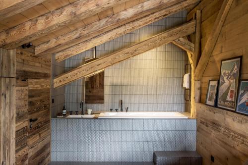La salle de bains est pourvue d'une baignoire et de murs en bois. dans l'établissement Chalet Drozin - Fenil LUXE & COZY 11 pers, à Abondance