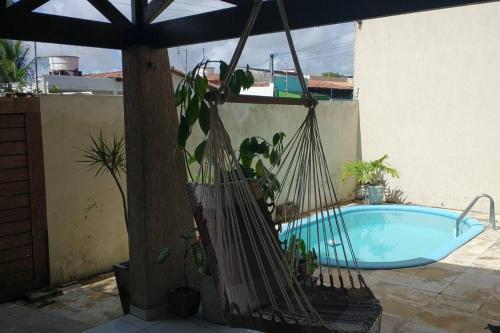 a hammock with potted plants next to a pool at Casa agradável com piscina 12 km da praia in Parnamirim