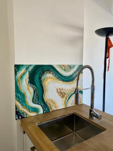 une cuisine avec un évier et un tableau mural. dans l'établissement Appartamento coeur du Suquet, à Cannes