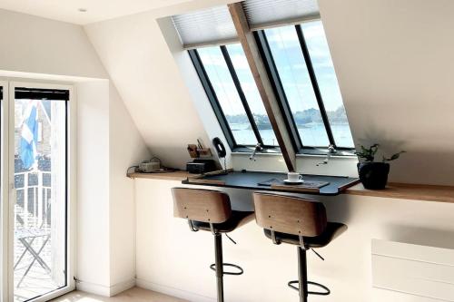 une pièce avec un bureau avec des chaises et des fenêtres dans l'établissement Appartement la Passerelle 2 Chambres, à Saint-Malo
