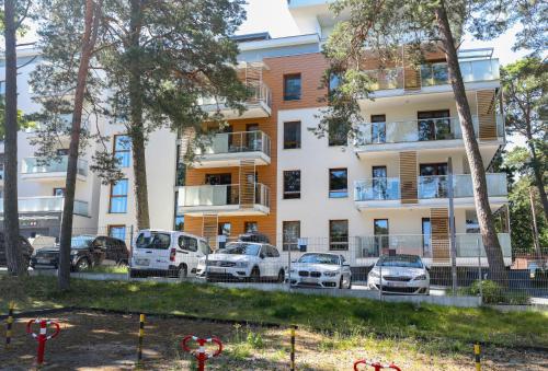 a building with cars parked in front of it at HoliApart in Nautikka Park - blisko plaży, kids club, plac zabaw, garaż podziemny in Krynica Morska