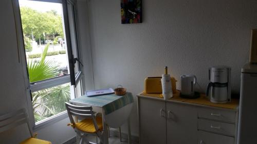 une cuisine avec un comptoir, une table et une fenêtre dans l'établissement Studio Cap d’Agde centre port, au Cap d'Agde