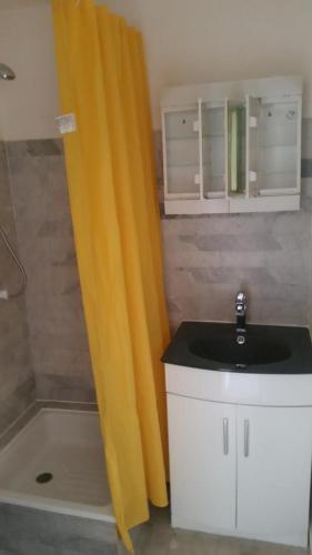 La salle de bains est pourvue d'un rideau de douche jaune et d'un lavabo. dans l'établissement Studio Cap d’Agde centre port, au Cap d'Agde