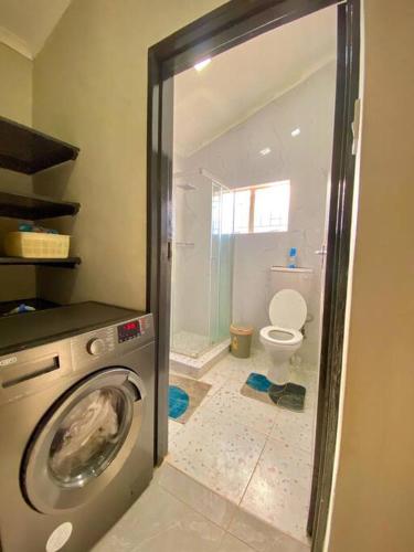 a bathroom with a washing machine and a toilet at Down Town Delight - 2BR Budget Retreat in Gaborone