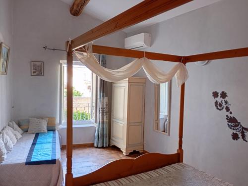 a bedroom with a canopy bed and a window at La Maison des Vendangeurs à Puisserguier in Puisserguier